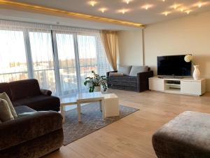 a living room with a tv and a couch and a table at Arunes Apartments - Daukanto in Palanga