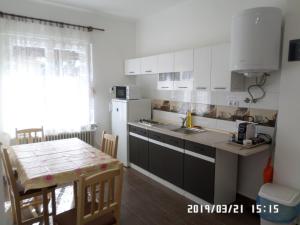 a kitchen with white cabinets and a table and a sink at Rita apartman in Szombathely
