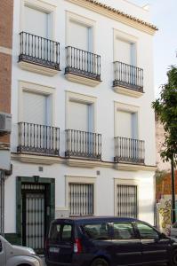 un coche negro estacionado frente a un edificio blanco en Apartamentos Océanos, en Málaga
