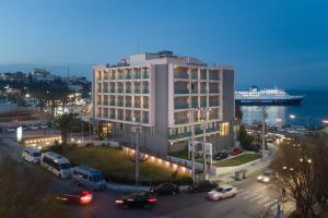 un grand bâtiment avec des voitures garées dans un parking dans l'établissement Hotel Avra by Smile hotels, à Rafína