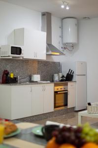 uma cozinha com armários brancos e um forno laranja em Apartamentos Océanos em Málaga