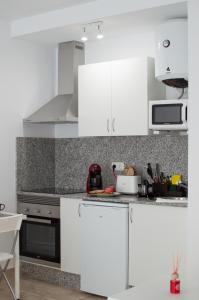 a white kitchen with white cabinets and appliances at Apartamentos Océanos in Málaga