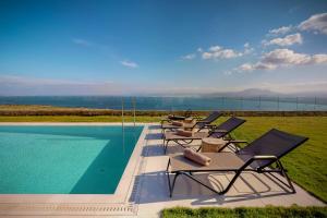 a row of lounge chairs next to a swimming pool at Ocean Villas Complex in Agia Pelagia