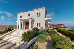 une maison blanche avec des escaliers et des buissons dans l'établissement Ocean Villas Complex, à Agia Pelagia