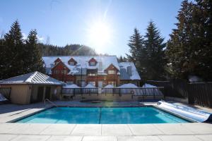 a house with a swimming pool in the snow at Lake Placid Lodge by Whiski Jack in Whistler