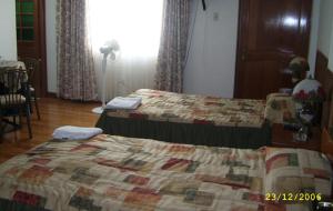 a bedroom with two beds and a table and a window at Hostal Camiluz in Nazca
