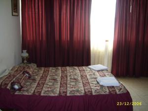 a bedroom with a bed with red curtains and a window at Hostal Camiluz in Nazca