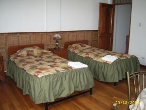 two beds in a room with wooden floors at Hostal Camiluz in Nazca