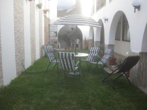 a patio with chairs and a table and an umbrella at Hostal Camiluz in Nazca