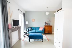 ein Wohnzimmer mit einem blauen Stuhl und einem TV in der Unterkunft ElbQuartier Apartments Magdeburg 'Die Stadtoase' in Magdeburg