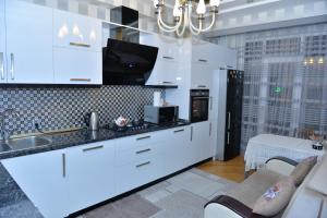 uma cozinha com armários brancos e um balcão preto em House Impulse Xazar em Baku