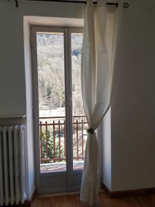 une fenêtre avec un rideau et une vue sur un balcon dans l'établissement Hostsrevolution Pragelato, à Pragelato
