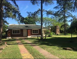 una pequeña casa en un patio con árboles y césped en Casa Quinta Corrientes en Corrientes