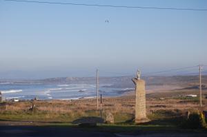 a statue of a man standing on a hill next to the ocean at Hostal Balieiros Corrubedo in Corrubedo