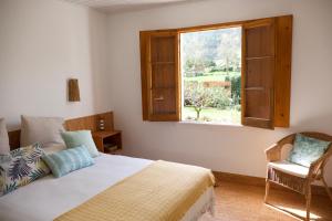 a bedroom with a bed and a window and a chair at #Areias Houses 9 in Furnas +29 photos
