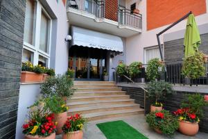 a building with stairs and potted plants and a green lawn at Hotel Olympic in Diano Marina