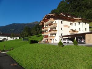 un grande edificio bianco su una collina con un campo verde di Ferienhof Nogler a Zellberg