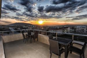 a balcony with tables and chairs and a sunset at EL NAZAR STONE SUİTE in Uçhisar