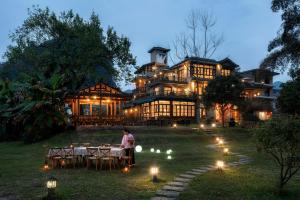 a woman sitting at a table in front of a large house at Moondance Boutique Resort in Yangshuo