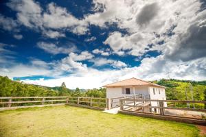 Ein weißes Haus auf einem Feld mit einem Zaun in der Unterkunft Pousada Bela Vista in Conceição da Ibitipoca