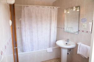 y baño con cortina de ducha y lavamanos. en Hostal Susi en Peñíscola