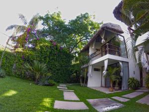 a house with a thatch roof and a grass yard at Mocca Hotels in Tepoztlán