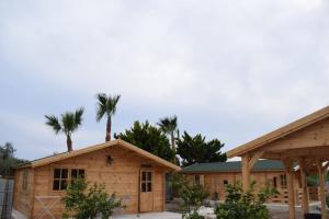two log homes with palm trees in the background at Cyprus Glamping Park in Ayios Theodhoros