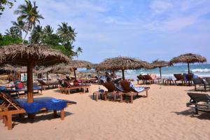una spiaggia con sedie e ombrelloni e l'oceano di skyresort a Tangalle
