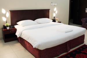 a hotel room with two beds and two lamps at Sahara Hotel Apartments in Muscat