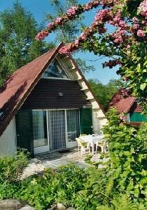 a house with a gazebo with a table and flowers at Casetta Allegra Terreno C27 in Brezzo