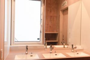 a bathroom with two sinks and a large window at BEACH AND FIELD INN in Sapporo
