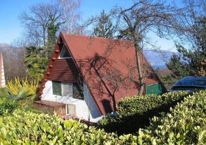 a house with a red roof and some bushes at Casetta Allegra Terreno C27 in Brezzo