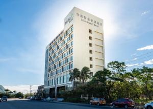 un alto edificio bianco con macchine parcheggiate di fronte di Rice Resort Hotel a Città di Taitung