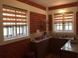 a kitchen with two windows and a brick wall at Marsim Holiday Resort in Vythiri