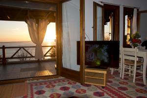 a living room with a television and a view of the ocean at House of the Rising Sun in Chorefto
