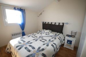a bedroom with a bed with a blue and white comforter at Maison de plage in Frontignan
