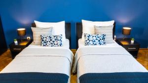two beds in a room with blue walls at Apartment Wake Up For 4 in Belgrade