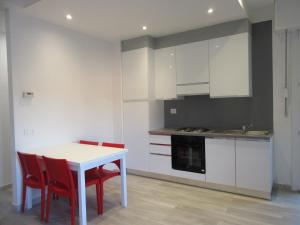 a kitchen with a white table and red chairs at Casa Azalea in Verbania +3 photos