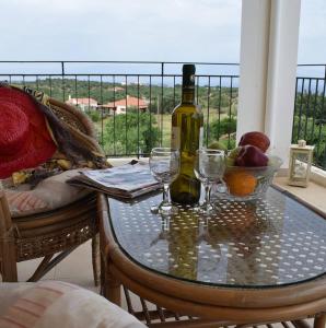 a glass table with a bottle of wine and glasses at Garden Villas in Koroni