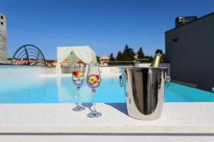 dos copas de vino y un cubo junto a una piscina en Apartments Mirakul, en Zadar
