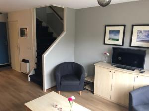 ein Wohnzimmer mit einer Treppe, einem Stuhl und einem TV in der Unterkunft Amelander Kaap 35 in Hollum