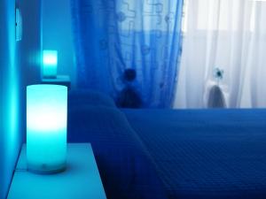 a blue room with a bed and a lamp on a table at pienosole B&B in Francavilla al Mare