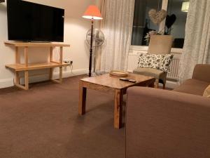 a living room with a couch and a table and a tv at Spacious 3 Bedroom Apartment in St. Albans
