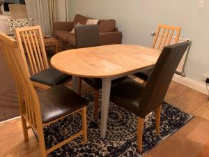 a wooden table with four chairs and a living room at Spacious 3 Bedroom Apartment in St. Albans