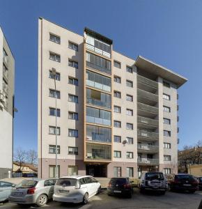 un grande edificio con auto parcheggiate in un parcheggio di Centro apartamentai-Konarskio apartamentai a Vilnius