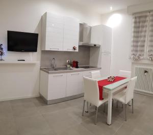 a kitchen with white cabinets and a red table and chairs at Sweet Home Sofia in Bologna