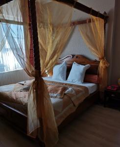 1 dormitorio con cama con dosel y almohadas blancas en Hôtel La Côte d'Or, en Philippeville
