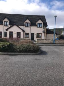 a white house with a black roof on a street at Christiesholidayhomes in Aviemore
