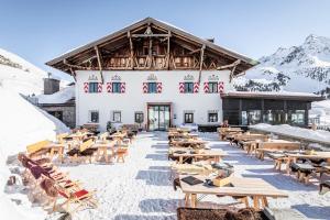 a large building with tables and benches in the snow at Hotel Jagdschloss Resort in Kühtai +148 photos