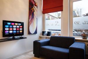 a waiting room with a chair and a flat screen tv at Suite 30 - kingsize groundfloor hotelapartment with parking in Groningen